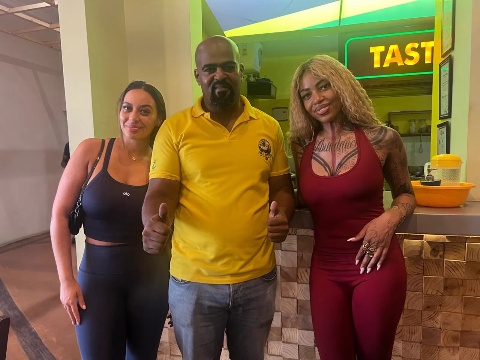 Visiting guests with a Jerk Harbour team member by the Taste Jamaica sign