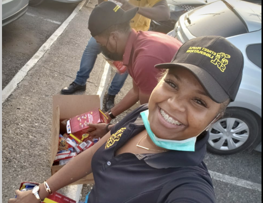 Every Mikkle Foundation volunteers in branded caps carrying a box of supplies at the roadside